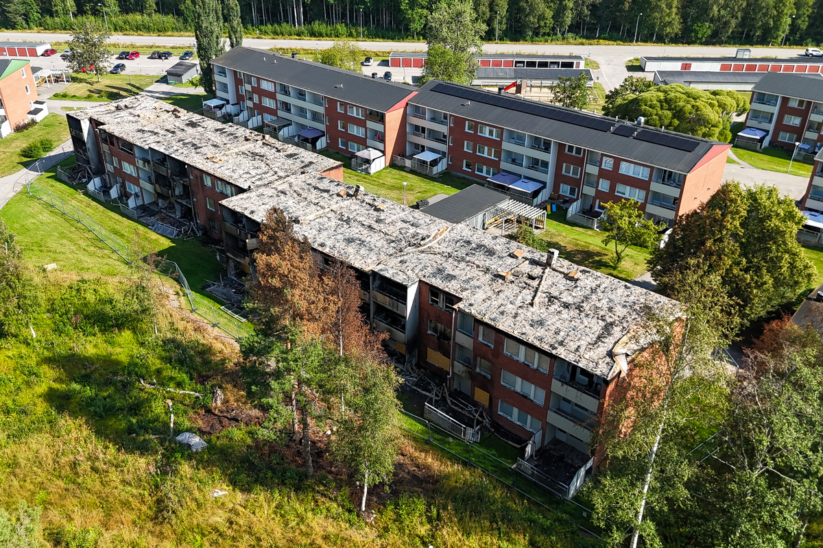 En flygbild av det brandrabbade huset på Stormyravägen 29-35 och dess omgivning.