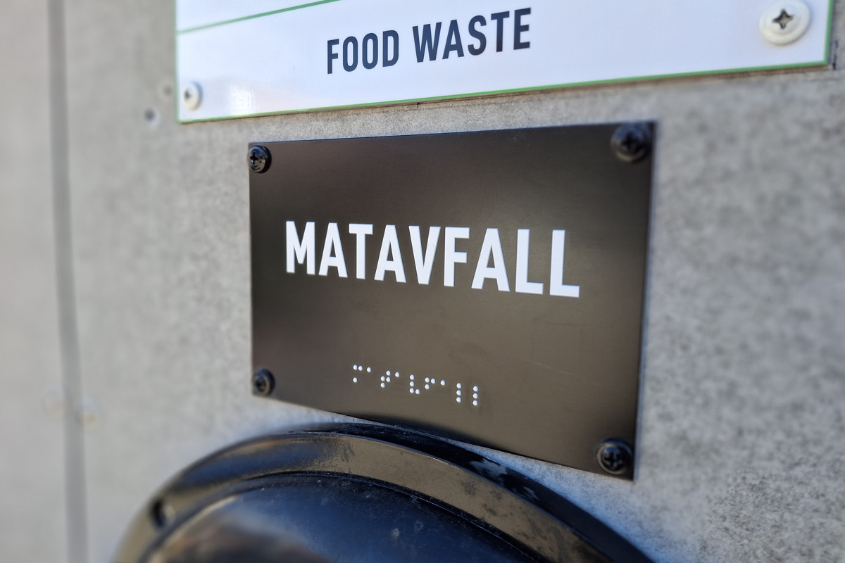 Bilden visar en skylt vid ett inkast för matavfall, med taktil text