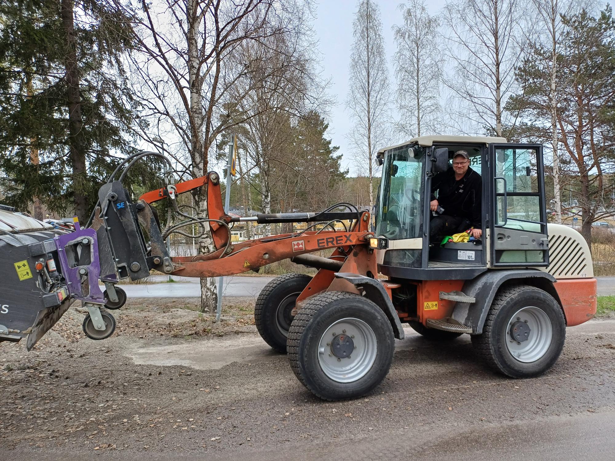 Bilden visar en lastmaskin med förare och grusupptagningsborste